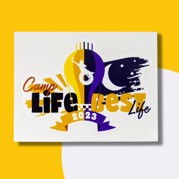 Image Description: Graphic image of Victory Junction's theme for 2023. A hot air balloon that is different shades of yellow and purple with VJ's tire swing boy in the middle of the balloon. On one side of the balloon there is a yellow background with a sun and the words "Camp Life." The other side says "Best life" with a moon and a dark purple background.